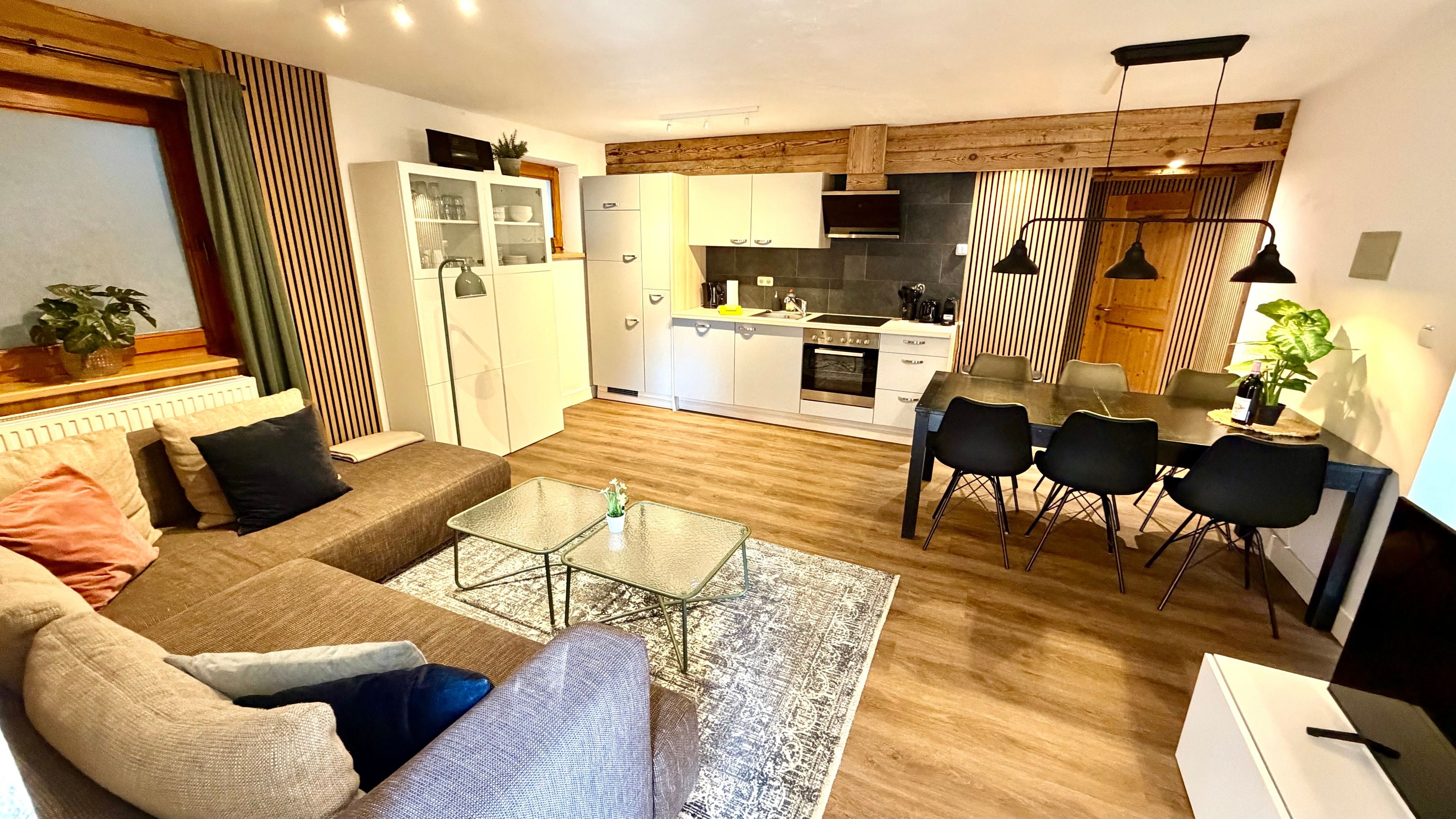 A modern living room with a sofa, a glass coffee table, and a dining area with a table and chairs.