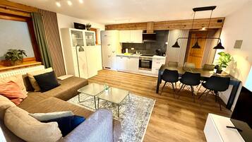 A modern living room with a sofa, a glass coffee table, and a dining area with a table and chairs.