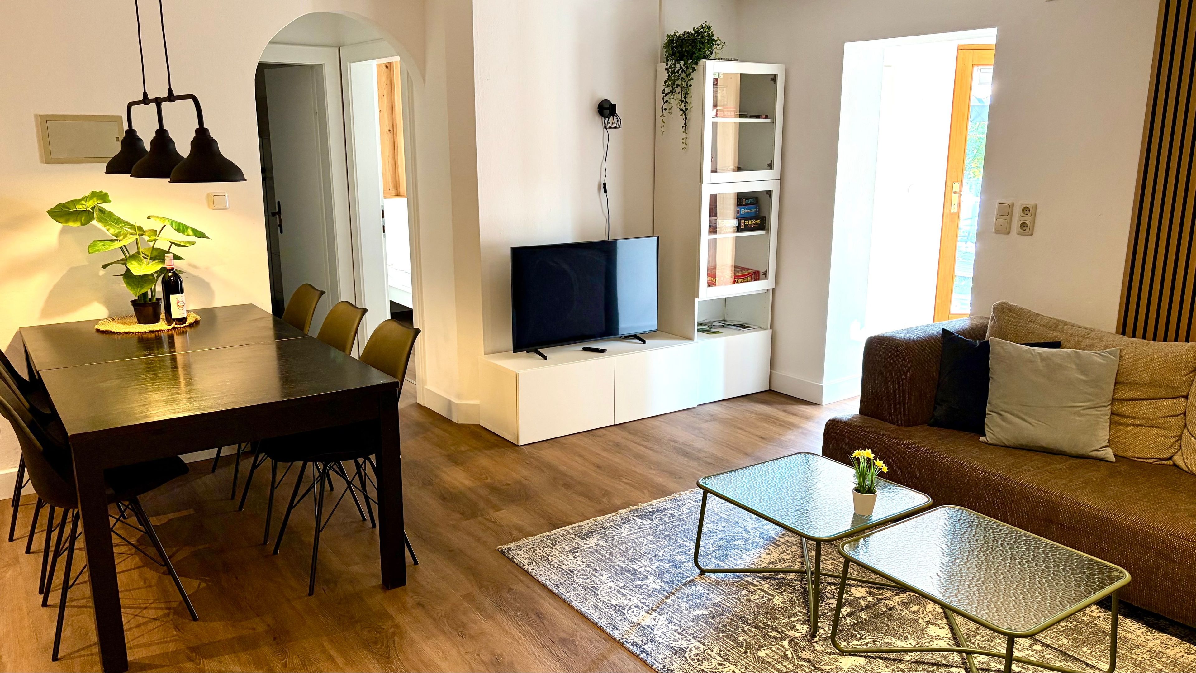 A modern living room with a dining area, a television, and a sofa.