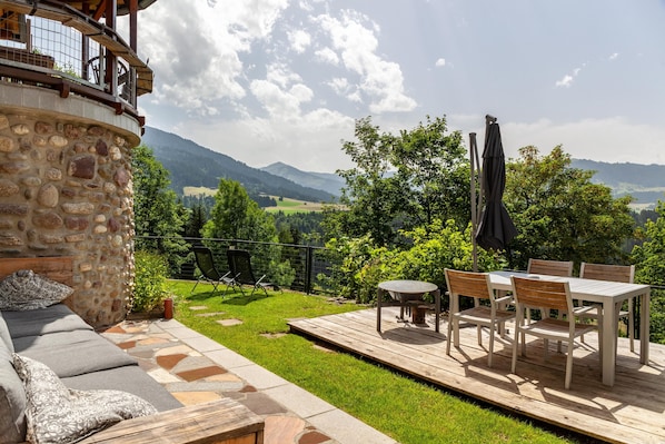 A stone building with a deck, outdoor furniture, and a scenic mountain view.