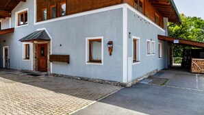 Un edificio de dos pisos con entrada de piedra, varias ventanas y un área exterior cubierta.