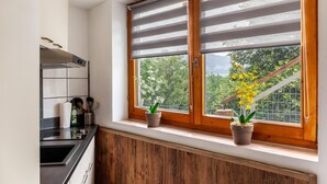 Una cocina con ventana, armarios de madera, estufa y dos macetas.