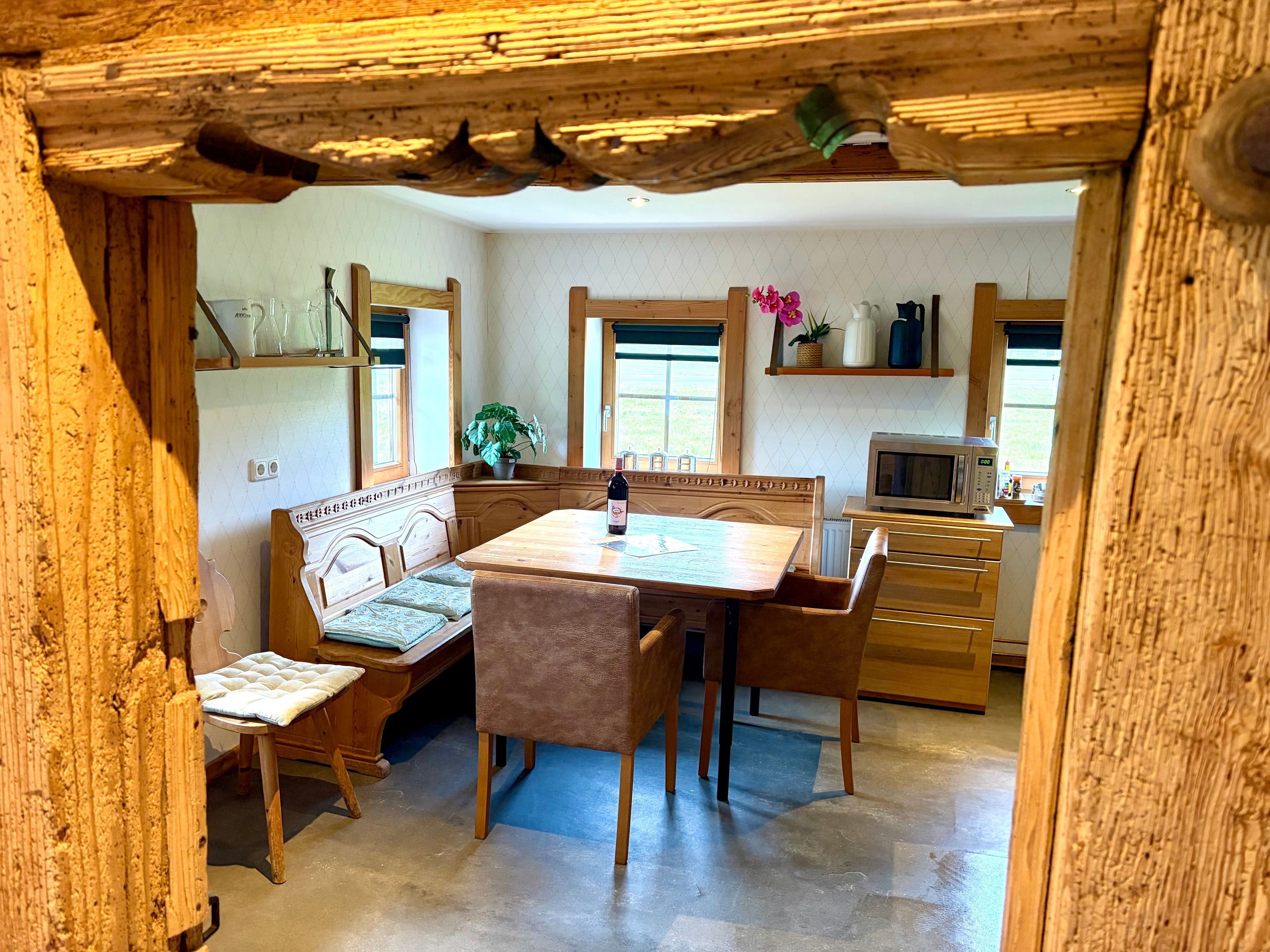 Un coin repas rustique en bois, avec un banc, une table et des chaises.