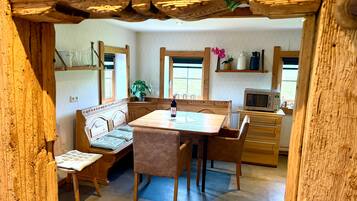 Un coin repas rustique en bois, avec un banc, une table et des chaises.