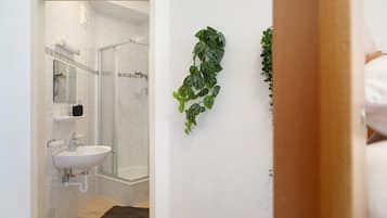 Un bagno con doccia, lavandino e specchio.
