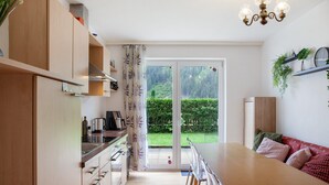 Una cocina moderna con armarios de madera, una mesa de comedor y vista a un jardín verde a través de un ventanal.