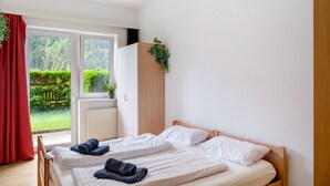 Un dormitorio con dos camas, un armario de madera y una ventana con vistas a zonas verdes.