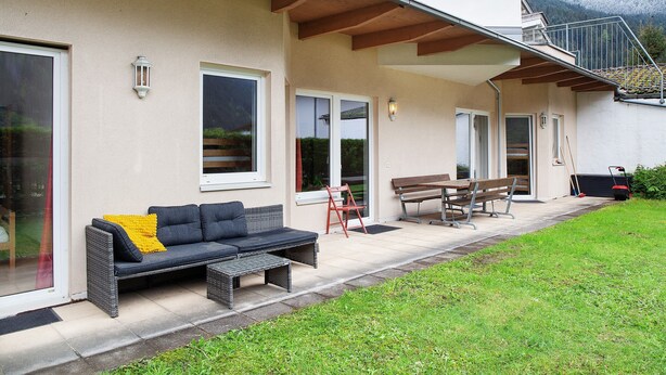 Una casa con un patio, un sofá, una mesa y un banco.