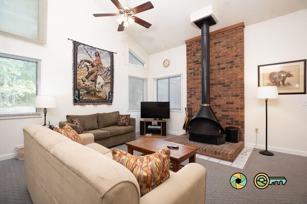 A living room with a sofa, a television, a fireplace, and a ceiling fan.