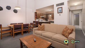 Un appartamento moderno con zona pranzo, divano e cucina sullo sfondo.