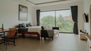A modern bedroom with a large bed, a sofa, a desk, and a TV.