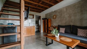 A modern living room with a wooden coffee table, a sofa, and a TV mounted on a wooden beam.