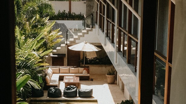 A modern indoor pool area with multiple pools, lounge seating, and potted plants.
