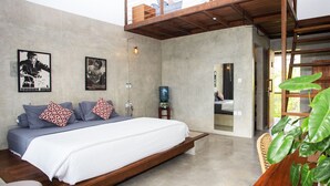A modern bedroom with a large bed, a wooden bench, a water dispenser, and a view of the outside.