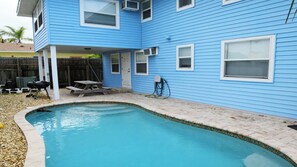 Ein Wohnhaus mit Swimmingpool, überdachter Terrasse und Grillplatz.