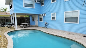 Ein Wohnhaus mit Swimmingpool, überdachter Terrasse und Grillplatz.