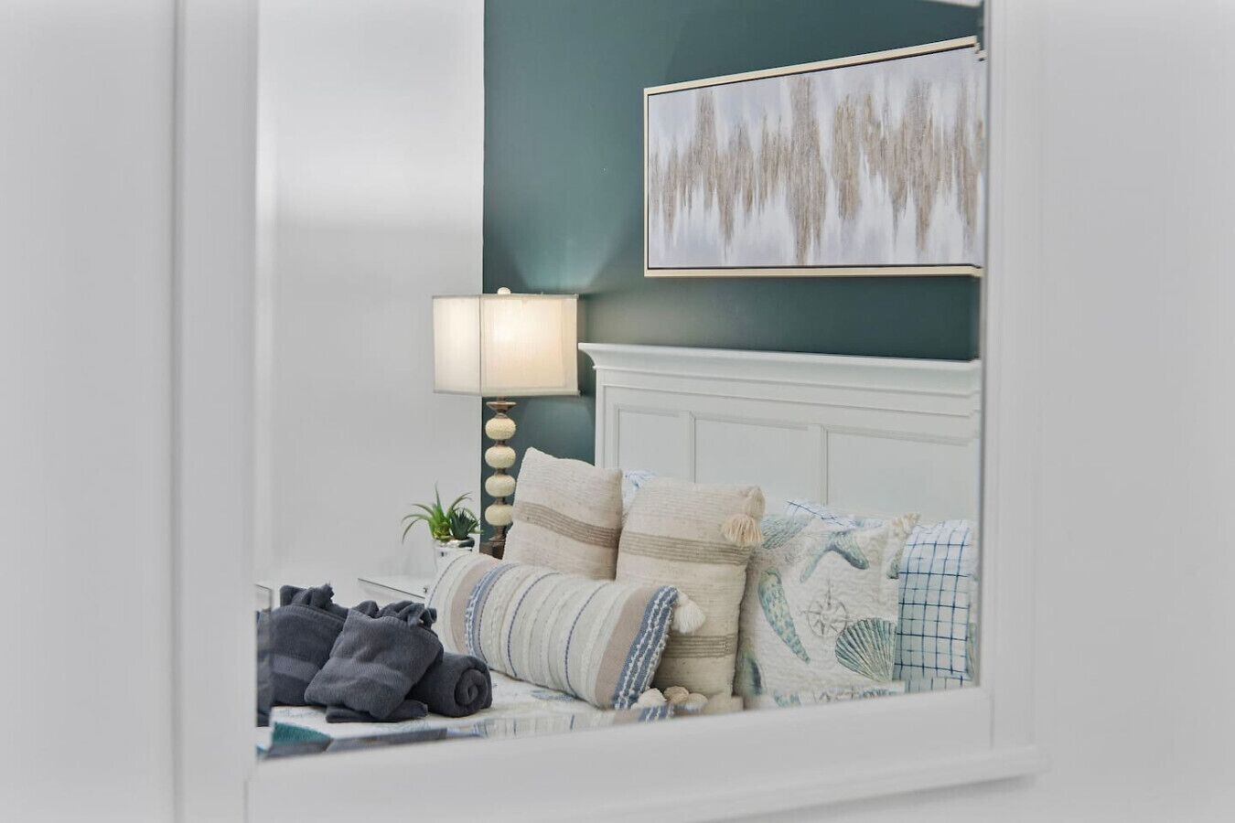 A neatly made bed with pillows and a blanket, a bedside lamp, and a wall-mounted picture.