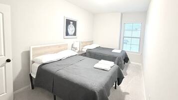 Ein Hotelzimmer mit zwei Betten, einem Fenster mit Jalousien und einem gerahmten Bild an der Wand.