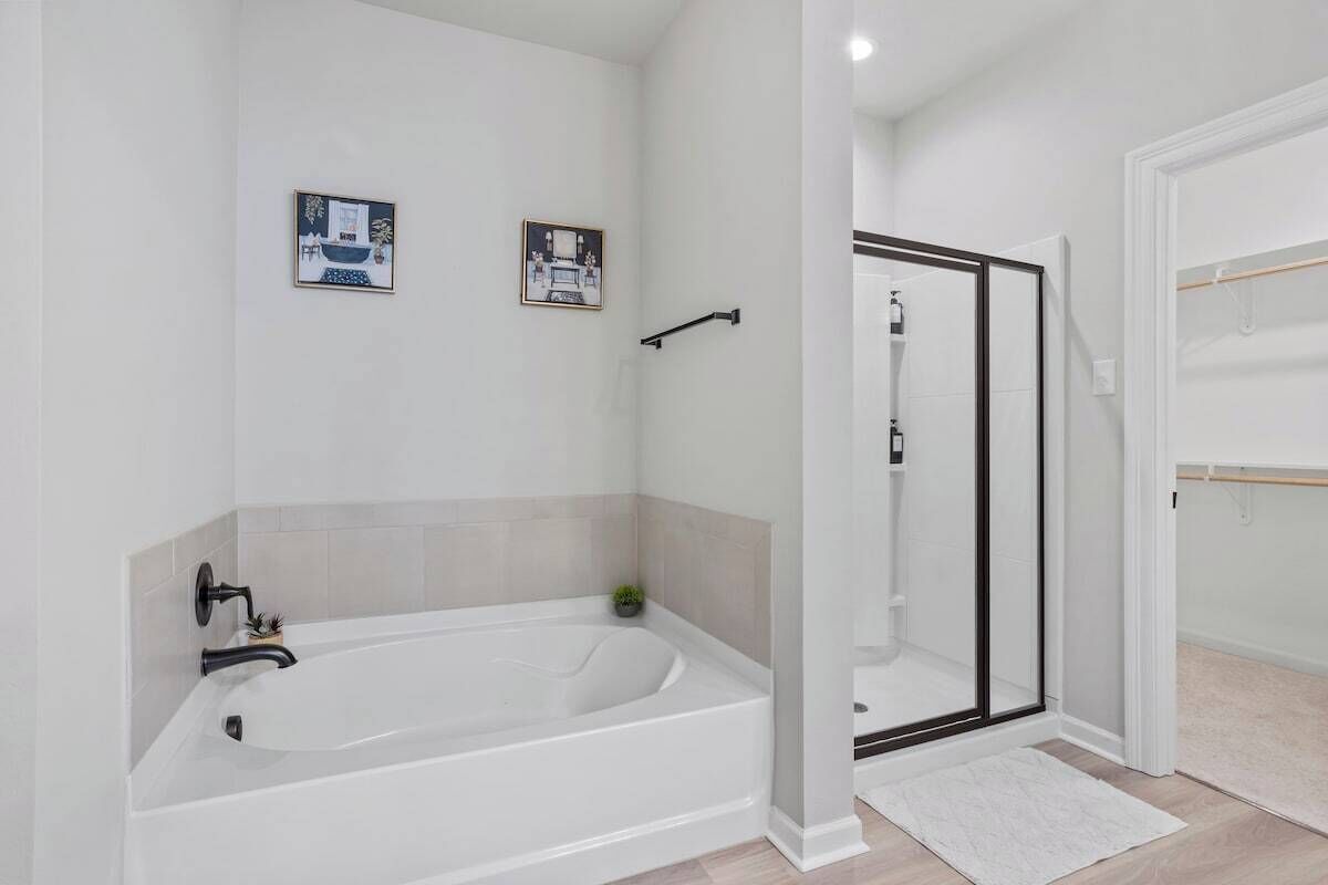 Une salle de bain moderne avec une baignoire sur pieds, une douche à parois de verre et un sol carrelé de carreaux blancs.