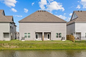 Une rangée de maisons à deux étages, dotées d’un toit plat, d’un garage à l’avant et d’un petit jardin.