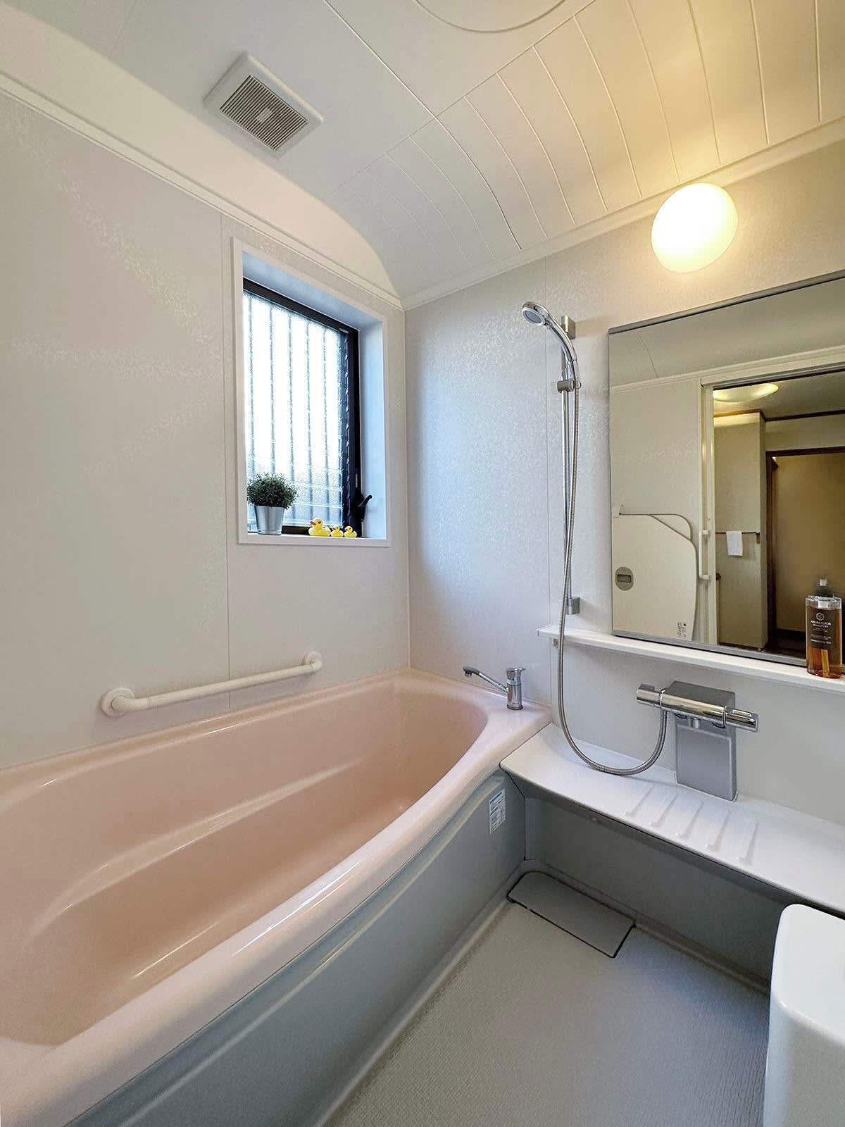 Un baño con una bañera grande, una ventana con persianas, una ducha y un espejo sobre el lavabo.