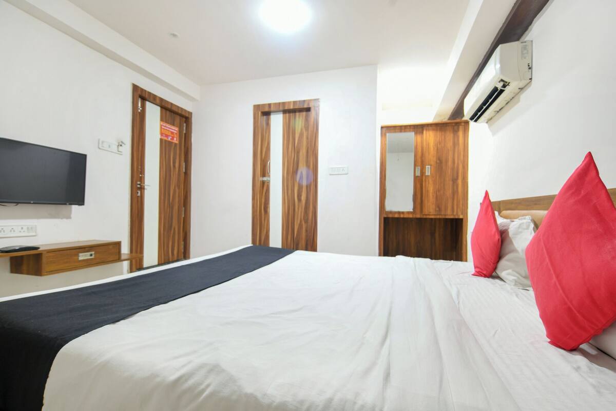 A hotel room with a bed, a TV, wooden wardrobes, and a wardrobe with a mirror.
