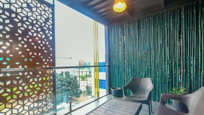 Uma varanda com móveis de vime, divisória de vidro e painel de bambu.