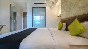 Una habitación de hotel con una cama grande, una mesita de noche, un espejo y un equipo de aire acondicionado.