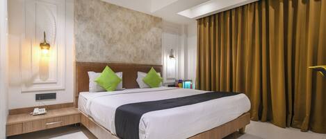 Una habitación de hotel con una cama grande, dos lámparas de noche, una mesita de noche, una luz en la pared y una ventana con cortinas.