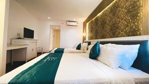A hotel room with a large bed, a desk with a computer, and a wall-mounted air conditioner. - Rivera Boutique (Da Nang)
