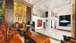 A lobby with a reception desk, a large golden mural, and a wooden reception area. - Rivera Boutique (Da Nang)