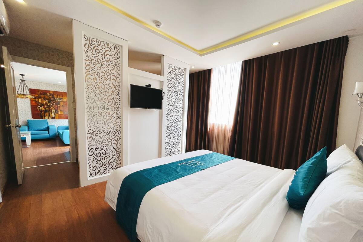 A hotel room with a large bed, a TV mounted on the wall, and a view of the hallway.