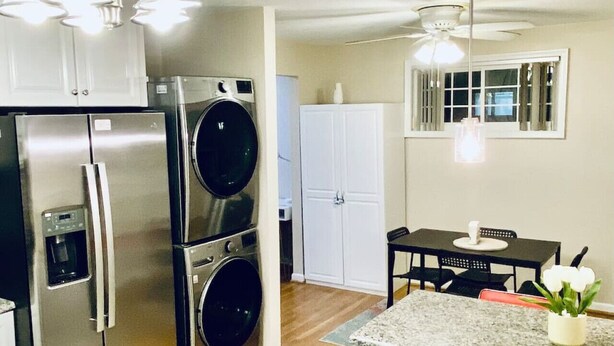 A compact kitchen with stainless steel appliances, a built-in oven, a dishwasher, and a dining area with a table and chairs.