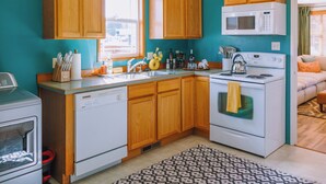 A compact kitchen with wooden cabinets, a microwave, a stove, and a dishwasher. - Mid-Mod Urban Hub | Hot Tub & Fire Pit (Port Angeles)