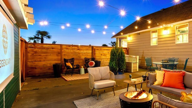A backyard with a fire pit, outdoor furniture, and string lights. - Mid-Mod Urban Hub | Hot Tub & Fire Pit (Port Angeles)
