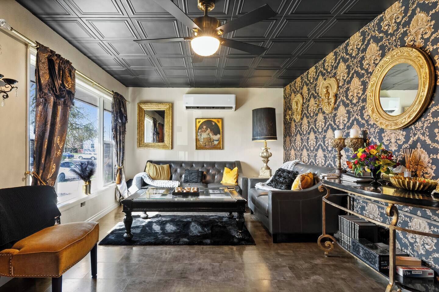 A living room with a sofa, armchair, and coffee table, a fireplace, and a decorative mirror.