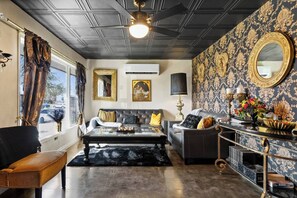 A living room with a sofa, armchair, and coffee table, a fireplace, and a decorative mirror.