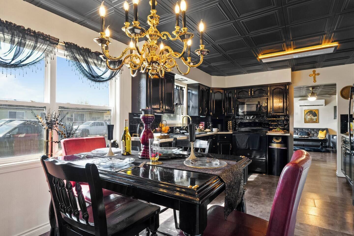 A dining area with a chandelier, a red chair, and a table set for four.