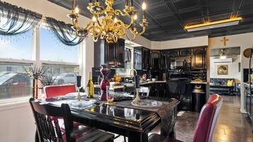 A dining area with a chandelier, a red chair, and a table set for four.