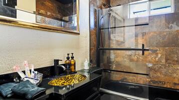 A bathroom with a black sink, a glass shower enclosure, and a mirror above the sink.