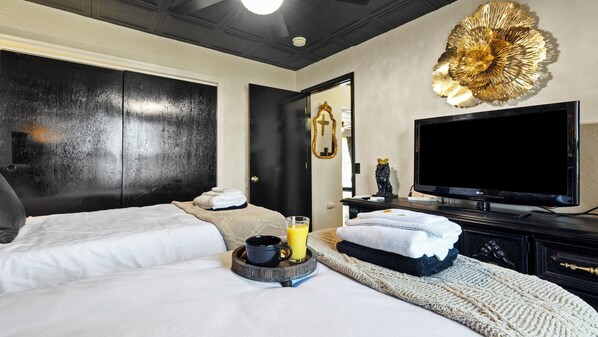 A hotel room with two beds, a large flat-screen TV, a decorative wall piece, and a mirror. - THE ONYX — A GOTHIC WINE-COUNTRY HOME WITH A HOT TUB, FIRE PIT AND GAME ROO... (College Place)