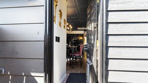 A narrow hallway with a wooden door on the left and a black door on the right.
