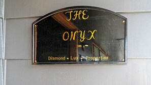 A sign with the text "THE ONYX" and "Diamond Lux Properties" on a reflective surface.