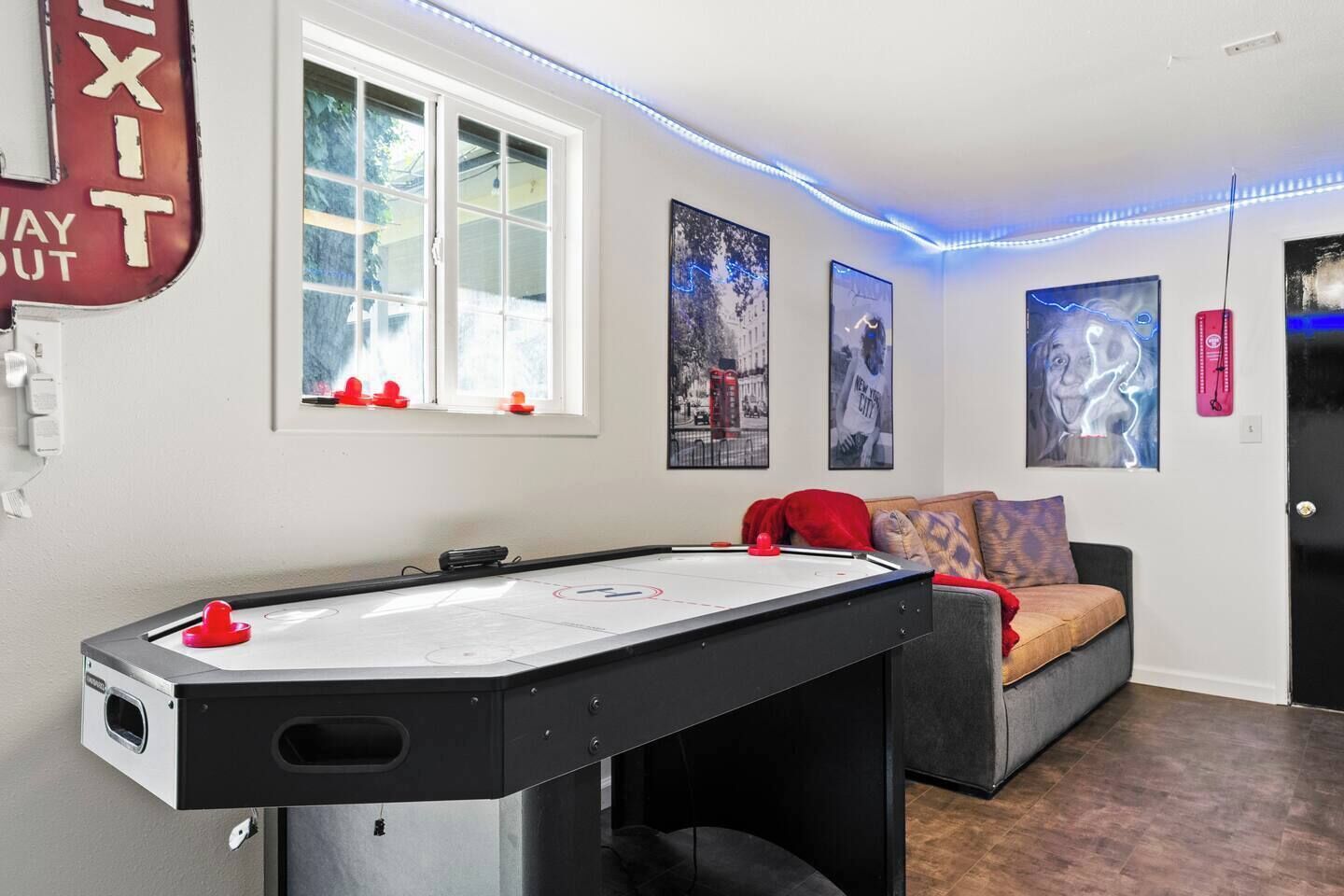 Ein Zimmer mit Billardtisch, einer Couch und einer Tür mit einem Ausgangsschild.
