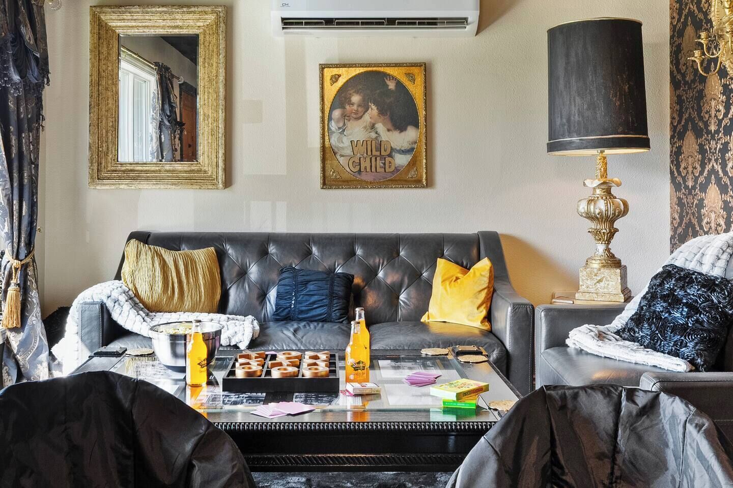 A living room with a leather sofa, a coffee table with snacks, a framed picture, and a lamp.