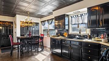 A kitchen with dark cabinetry, a chandelier, and a dining area with red chairs.