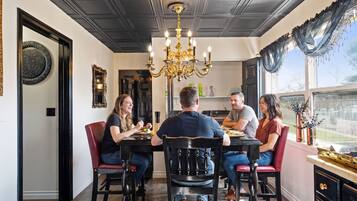 A dining area with a chandelier, a black dining table, and red chairs.