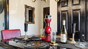A dining table set with a wine bottle, glasses, and a red candle holder.