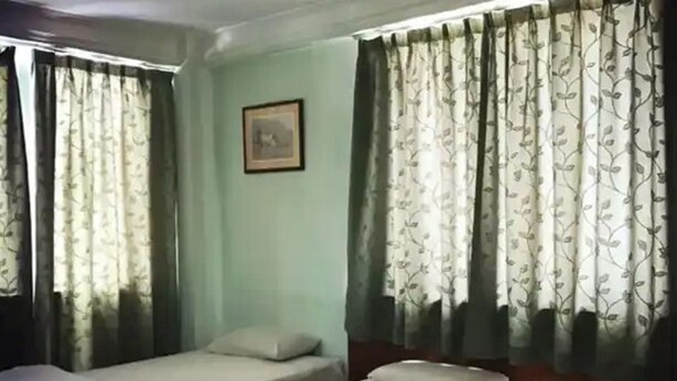 A room with two beds, each with a pillow and a blanket. There is a framed picture on the wall. - Hotel O Asia City (Kota Kinabalu)