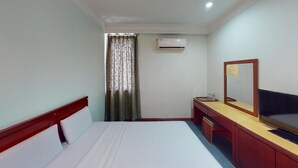 A hotel room with a bed, a desk with a mirror, a chair, an air conditioning unit, and a curtain. - Hotel O Asia City (Kota Kinabalu)